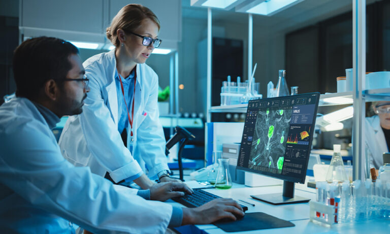 Researchers in a modern laboratory analyzing clinical trial data on a computer screen, representing how AI helps overcome challenges in clinical data management.